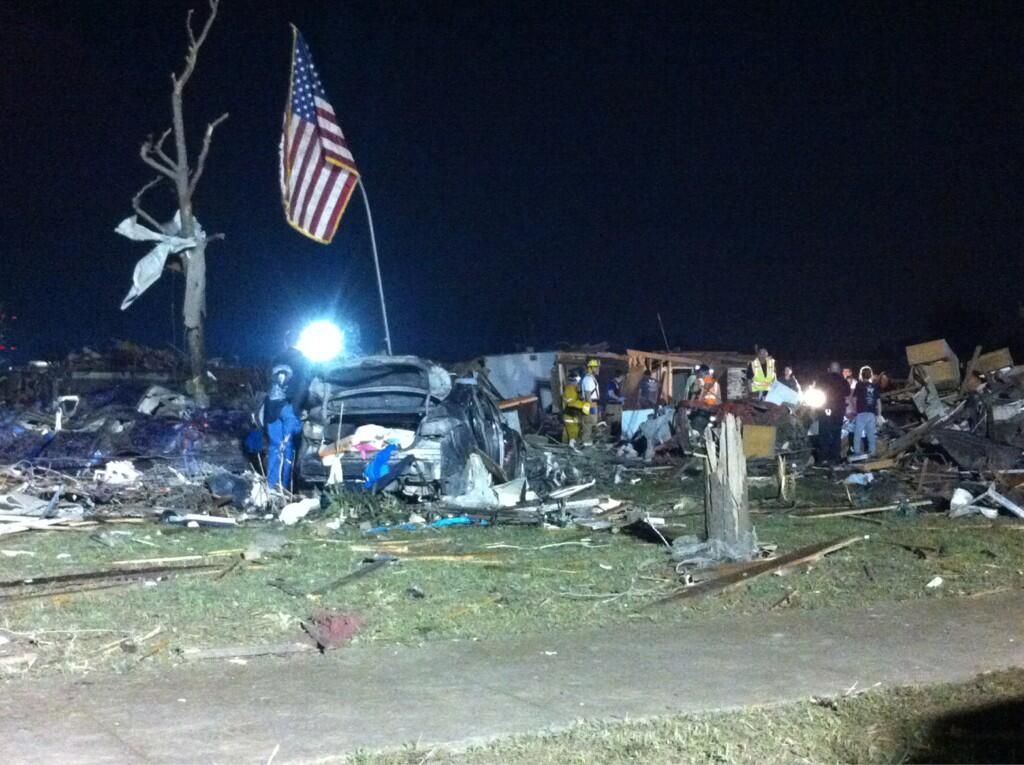 An American flag is raised from the rubble as the recovery effort continues the first night after the tornado in Moore, OK